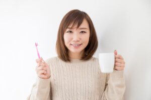 歯を白く保つためにうがいと歯磨きをする女性