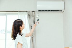 夏にエアコンの温度調整をしている女性