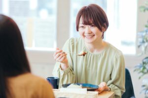 ホワイトニングした歯で友人と食事する女性のイメージ