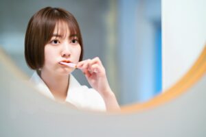 鏡の前で丁寧に歯みがきをする女性の様子。毎日のセルフケアで口元の健康を意識する姿